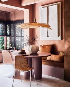 a dining room table with chairs and an umbrella hanging from it's ceiling in front of a window