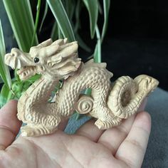 a hand holding a small wooden dragon figurine in it's palm area