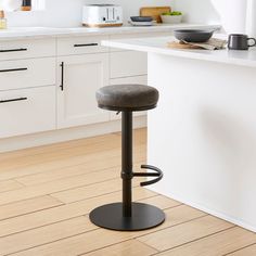 a modern kitchen with white cabinets and counter tops, along with a bar stool in the center