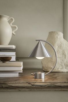 a table lamp sitting on top of a counter next to some books and a vase