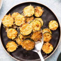 cooked zucchini on a black plate with a spoon