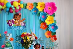 a birthday party with decorations and balloons on the wall, including cake, flowers, and tiki's