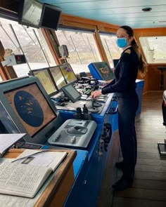 a woman wearing a face mask standing in front of a desk with electronic equipment on it