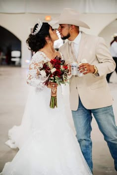 a bride and groom share a kiss in the middle of an indoor wedding venue with white walls