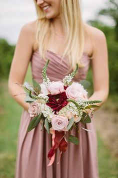 a bridesmaid holding a bouquet of flowers and greenery on her wedding day