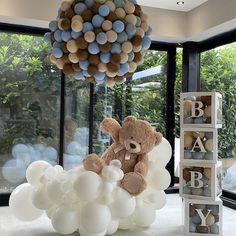 a teddy bear sitting on top of a bunch of balloons in front of a window