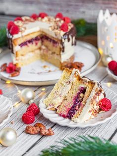 two pieces of cake on plates with raspberries and nuts around them, surrounded by christmas decorations