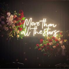 a neon sign that says more than all the stars with flowers in front of it