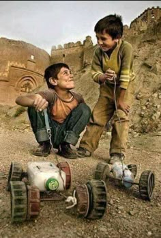 two young boys playing with toy cars in the desert