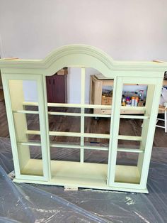 a green book shelf with glass doors on it's sides in a room that is being remodeled