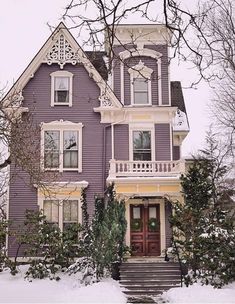 a purple house with snow on the ground and stairs leading up to it's front door