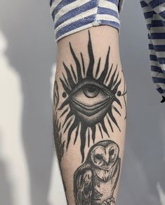 a person with an owl and sun tattoo on their leg, next to a striped shirt