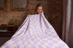 a woman holding up a purple and white checkered blanket