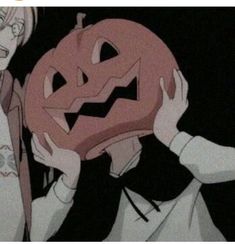 an anime character holding up a jack - o'- lantern in front of his face