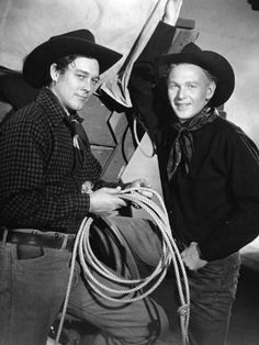 black and white photograph of two men in cowboy hats with rope around their waists