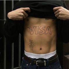 a person with tattoos on their stomach holding up his shirt to show the word visa