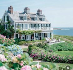 a large white house sitting on top of a lush green hillside next to the ocean