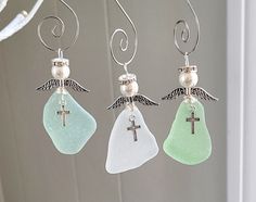 three sea glass angel earrings hanging from a wire