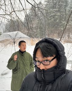 two people standing in the snow with umbrellas over their heads and one person holding an umbrella