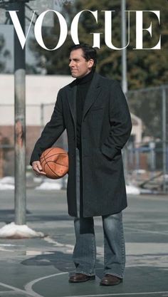 a man holding a basketball while standing next to a pole with the word voque on it