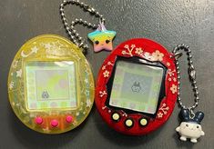 two electronic devices sitting next to each other on top of a wooden table with key chains