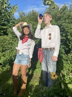 a man and woman dressed up in cowboy attire standing next to each other on grass