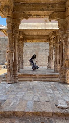 a woman is sitting on a stone bench in an old building with columns and pillars