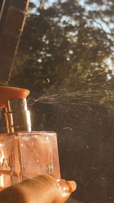 a person is spraying water from a sprinkler in the air with their hands