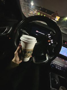 a person holding a cup in their hand while driving