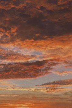 an airplane is flying in the sky at sunset