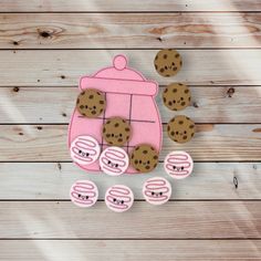 a pink oven with chocolate chip cookies in it on a wooden table next to some cut outs