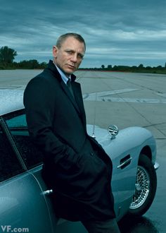 a man in a suit leaning on the hood of a car