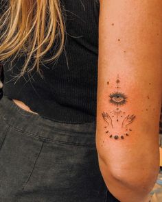 a woman's arm with a tattoo on it that has an evil eye and two hands