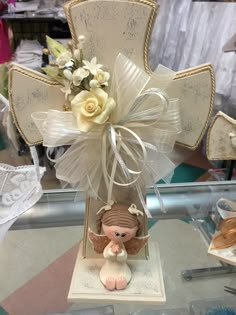 a cross shaped vase with flowers in it on a glass table next to other items