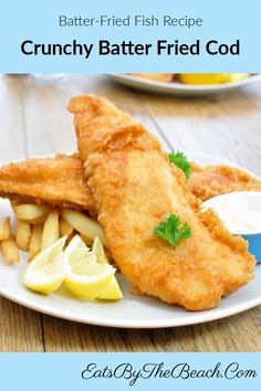 fish and chips on a white plate with lemon wedges