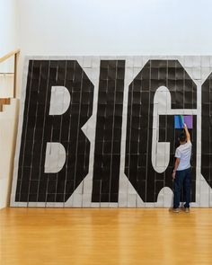 a little boy standing in front of a big sign with the word big on it