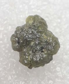 a piece of green rock sitting on top of a white surface