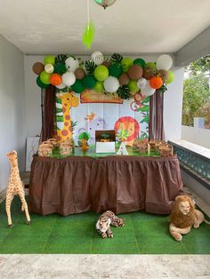 a jungle themed birthday party with balloons, decorations and stuffed animals on the floor in front of a table