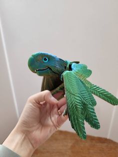 a person holding a toy bird with green leaves on it