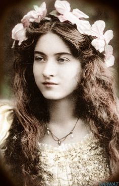 an old photo of a young woman with long hair and flowers in her hair, wearing a flower crown