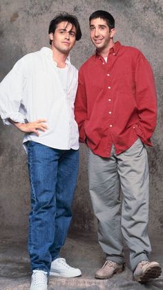 two men standing next to each other in front of a wall