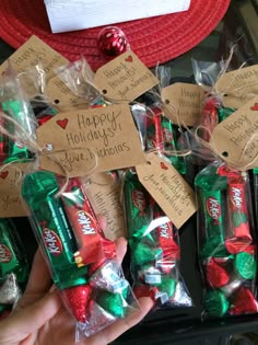 hand holding candy wrapped in cellophane with holiday messages on them and christmas candies