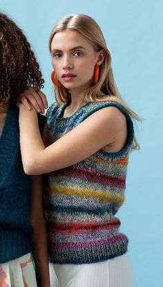 two women standing next to each other wearing colorful sweaters and matching earring earrings