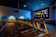 a gym with rows of treadmills in front of a sign that reads choose fitness