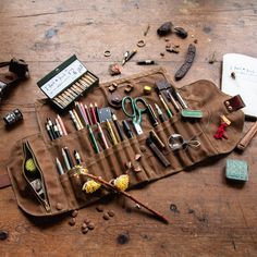 an assortment of pens, pencils, and other items on a wooden table with writing utensils