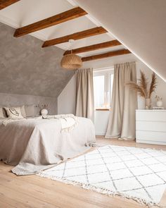 a bedroom with a white rug and wooden beams on the ceiling is decorated in neutral colors