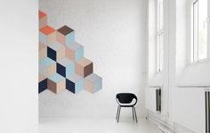 a chair sitting in front of a wall with an abstract painting on it's side