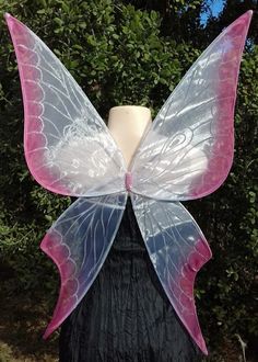 a white and pink butterfly wings on top of a mannequin's head