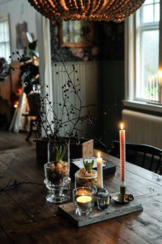 a wooden table topped with candles and vases