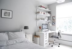 a bedroom with a bed, desk and bookshelf next to a large window